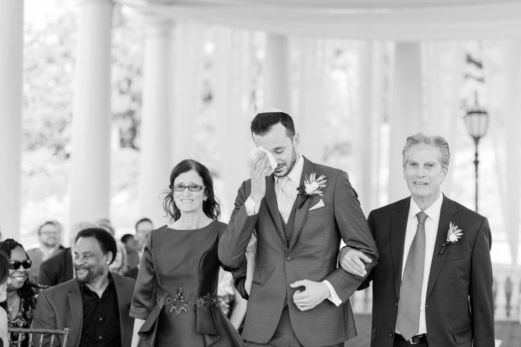 groom walking down aisle with his parents
